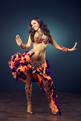 Obraz premium Beautiful slender dancer , belly dance in motion in a colorful costume .Dancer in motion in carnival costume 