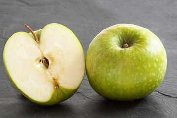 Pommes Granny-Smith et moitié sur fond ardoise