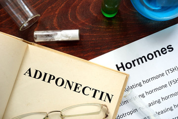 Hormone adiponectin written on book. Test tubes and hormones list.