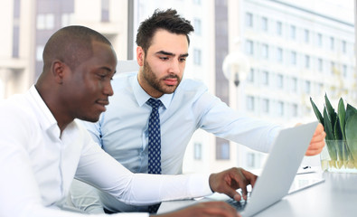 Image of two young businessmen interacting at meeting in office