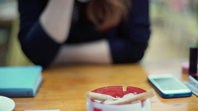 Woman sitting at wooden table and smoking cigarette
