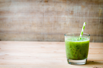 Healthy green smoothie in a glass on old wood.