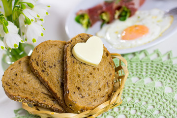 Bread with a heart of butter, fried eggs with bacon.