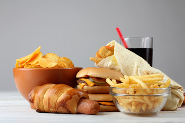 Big appetizing hamburger with fries and a coke and chips on white wood table