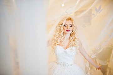 Curly blonde bride  posing on curtains