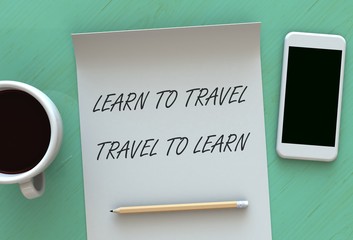 Learn to Travel Travel to Learn, message on paper, smart phone and coffee on table