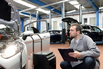 Gutachter untersucht Auto in einer Werkstatt - TÜV Kontrolle in Deutschland - obrazy, fototapety, plakaty