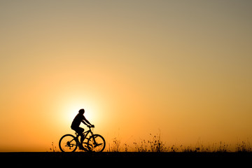 Obraz premium Silhouette of cyclist motion on sunset background