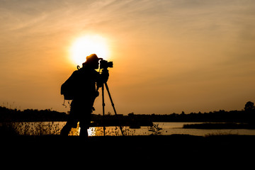 Silhouette photographer in sunset background