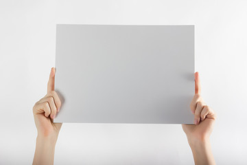 Hands holding a white paper blank isolated on white background