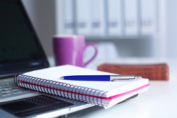 Office table with blank notepad and laptop 