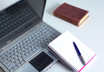 Office table with blank notepad and laptop 