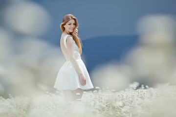 Fototapeta na wymiar Beautiful young woman in a camomile field 