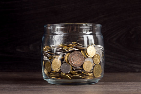 Moneybox with gold and silver coins on wooden background