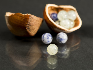 Hazelnut shell with small blue and transparent gemstones on dark background