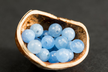 Hazelnut shell with small blue and transparent gemstones on dark background