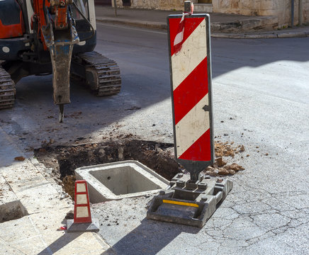 excavator with hydraulic hammer used for the realization of a cockpit in cement with cast iron manhole