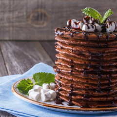 Stack of pancakes with marshmallow and chocolate syrup.