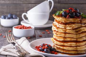 Stack of pancakes with fresh blueberry, goji  and maple syrup.