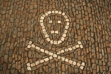 Symbol of crossed bones and skull created from white cobbles on the ground. Taken in Sedlec, Kutna Hora ossuary, Czech Republic