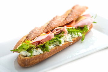 long sandwich with ham, cheese, tomatoes and lettuce. Isolated on white background