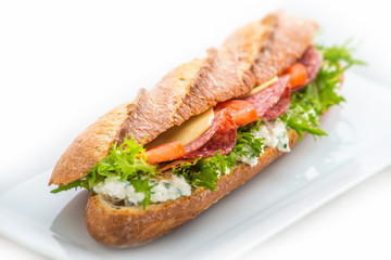 long sandwich with ham, cheese, tomatoes and lettuce. Isolated on white background