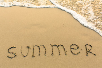 Summer - word drawn on the sand beach with the soft wave.