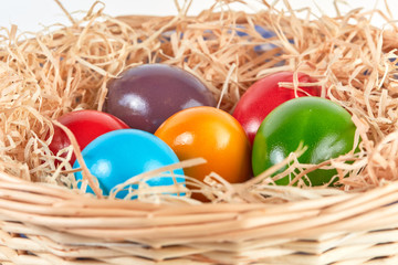 Easter basket with colored eggs and straw
