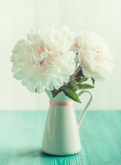 White peonies in floral vase on mint wooden table, vintage colors