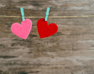 Fototapeta premium two red and pink hearts hanging on a cord 