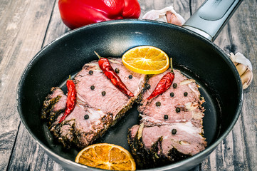 Frying meat in pan on wooden background