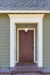 Fototapeta na wymiar Narrow front door with white trim and green facade
