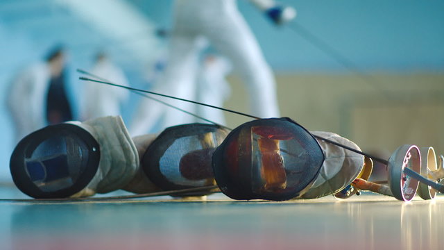 fencing mask and foil and fencers on background