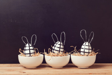 Modern easter egg decorations with bunny ears on chalkboard. Creative easter background.