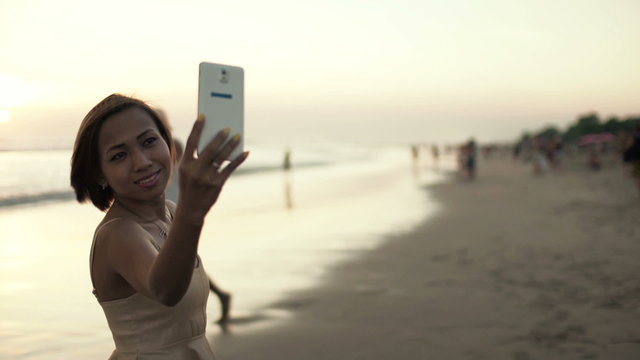 Young, attractive woman taking selfie photo on beautiful beach
