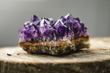 Raw amethyst rock with reflection on natural wood crystal  ametist - obrazy, fototapety, plakaty