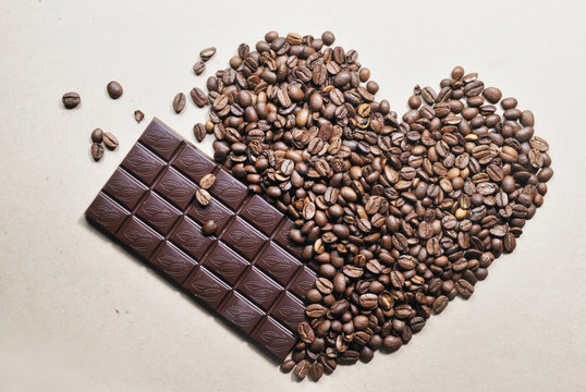 photo of heart shaped coffee beans and chocolate bar on beige background