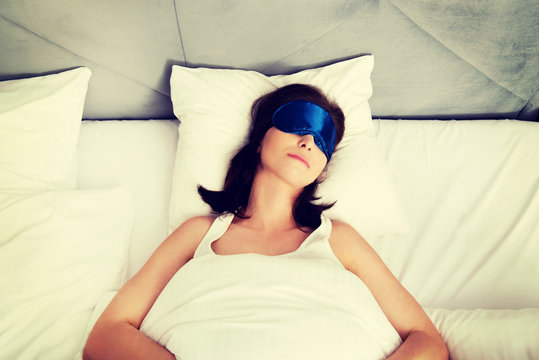 Woman sleeping in bed with eyes band.