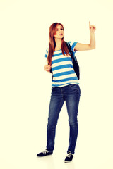 Teenager woman with backpack pointing for soomething