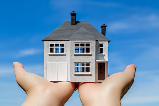 House in hands with sky background