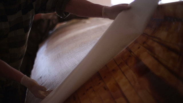 Construction of boats at the shipyard, gluing fiberglass on the side of the boat with resin
