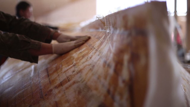 Construction of boats at the shipyard, gluing fiberglass on the side of the boat with resin
