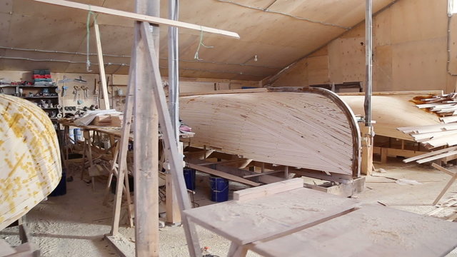 Construction of a boats at the shipyard, the frames has been covered with wooden planks, the seams plastered with resin
