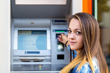 young woman inserting credit card at ATM
