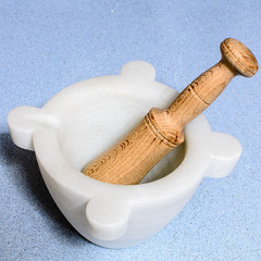 A homemade marble's pestle over a blue silestone desk with garli