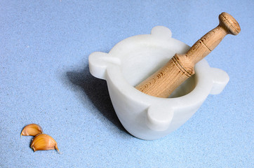 A homemade marble's pestle over a blue silestone desk with garli