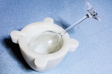 A mortar made of marble on a blue marble surface with a cup of wine