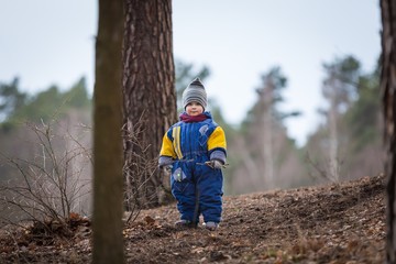 Little caucasian boy playing in forest at early spring