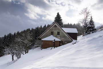 Snow covered house in a frosty mountains country in sunny winter day