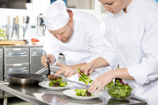 Two chefs prepares steak dish at gourmet restaurant